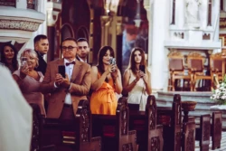 Rolki Ślubne Goście weselni robią telefonami zdjęcia pary młodej, która wchodzi do kościoła.