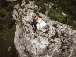 Sesja ślubna w górach Para młoda całuje się siedząc na skalnym klifie w górach. Surowy klimat skał.