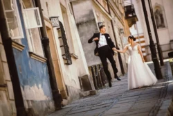 Fotograf ślubny Młoda Para spacerująca ulicami Starego Miasta w Warszawie. Szalony podskok Młodego Pana i uśmiechnięta Panna Młoda