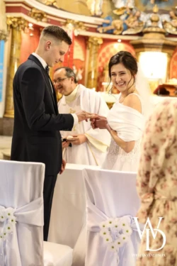 inspiracje ślubne Szczęśliwa panna młoda nakłada panu młodemu obrączkę podczas ceremonii w kościele.