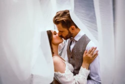 Romantyczny pocałunek pary młodej Para młoda całuje się pod ślubnym welonem w romantycznym kadrze.